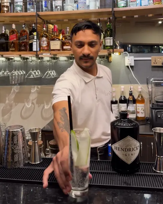 Bartender serving a tall gin and tonic